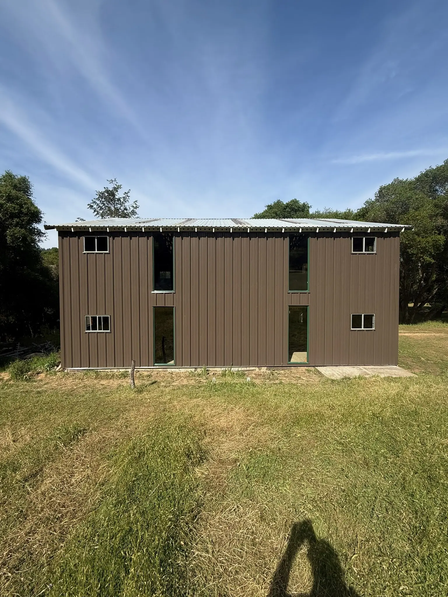 Completed long elevation with dark vertical metal siding and new windows