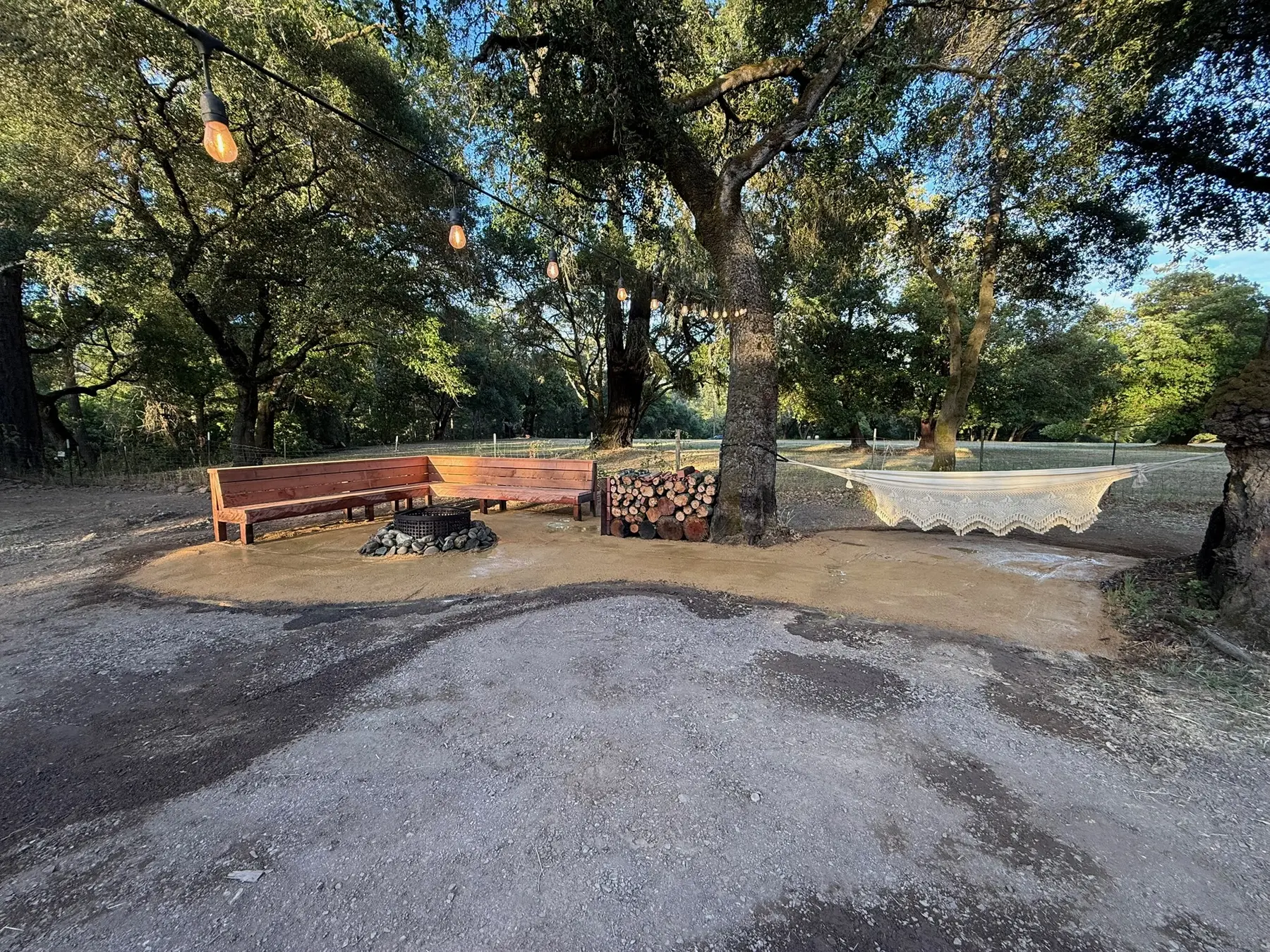Poleeko firepit, redwood seating and wood storage beneath oak trees